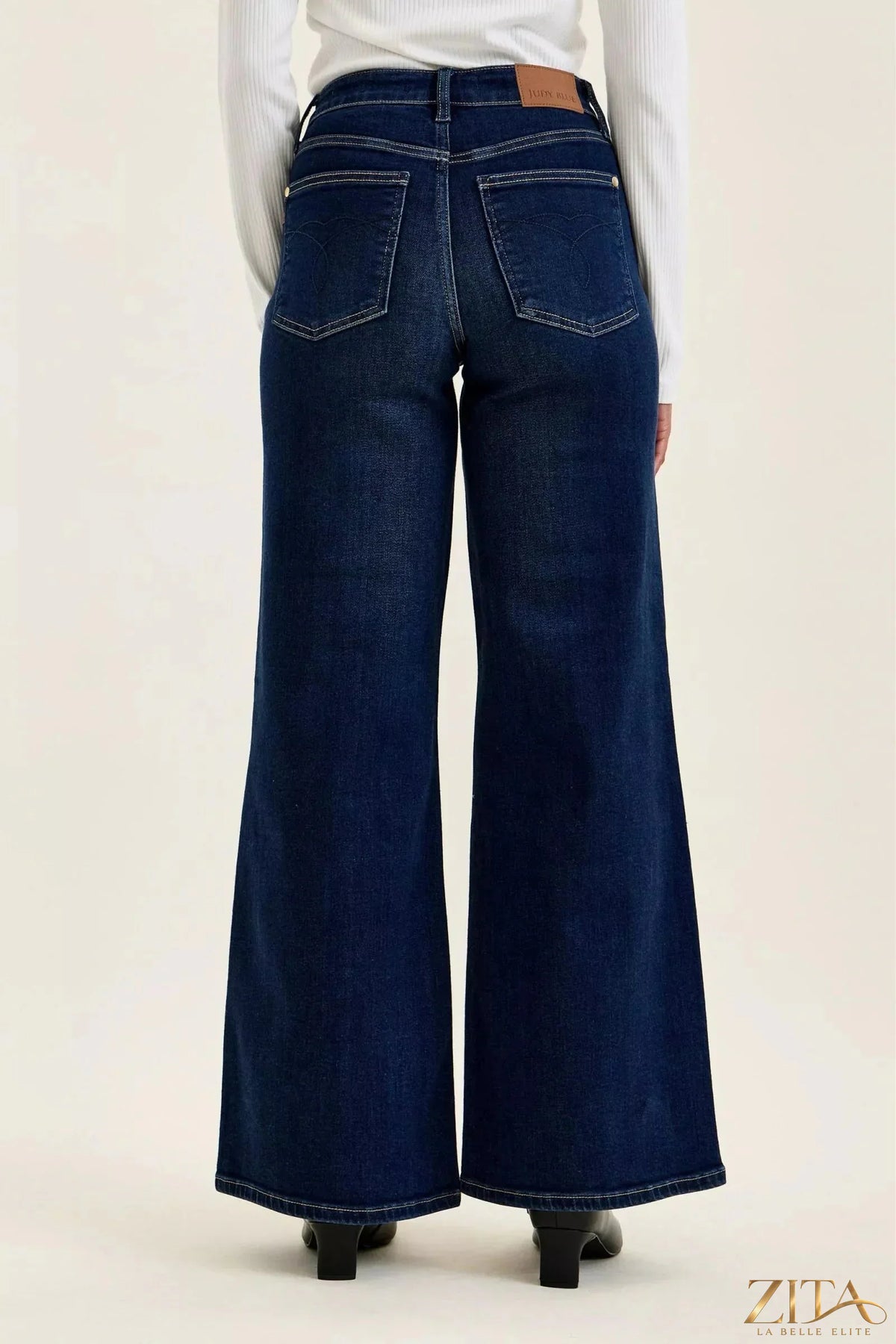 Dark wash Judy Blue high-waisted wide-leg jeans displayed on a hanger with visible stitching and relaxed fit.
