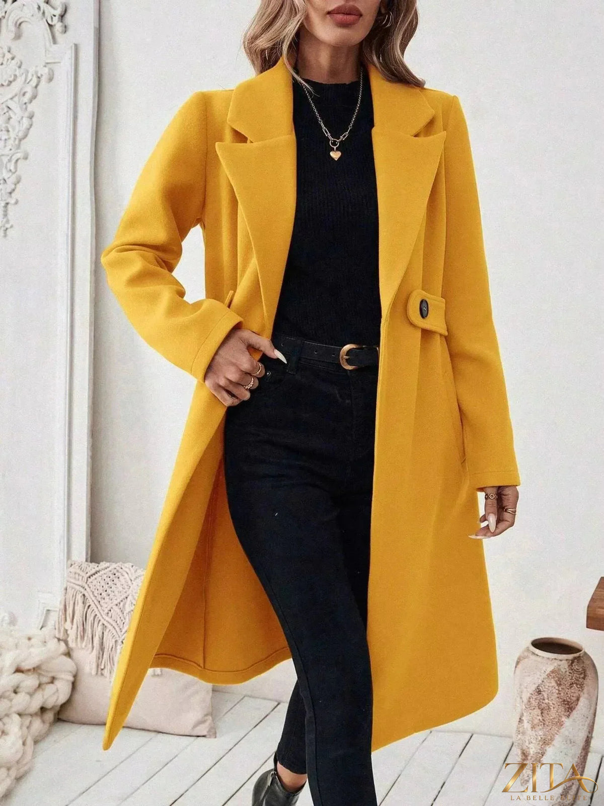 Zita La Belle Elite single-button longline coat in neutral fabric, shown hanging on a wooden background.