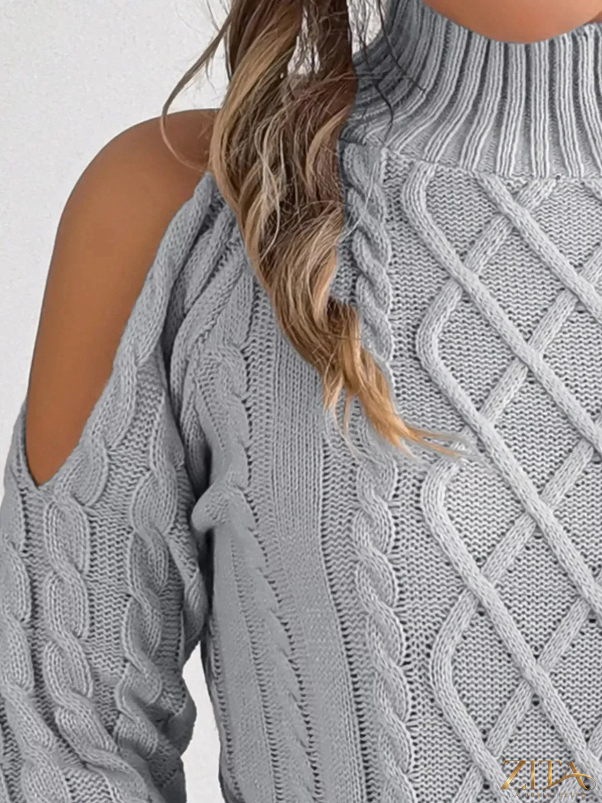 Zita La Belle Elite cold-shoulder cable knit sweater in soft beige, featuring open shoulders and textured knit design.