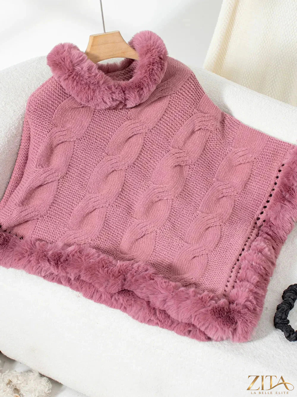 Fuzzy hem cable-knit poncho in neutral tones, featuring a cozy oversized style with textured knit details and fringe hem.
