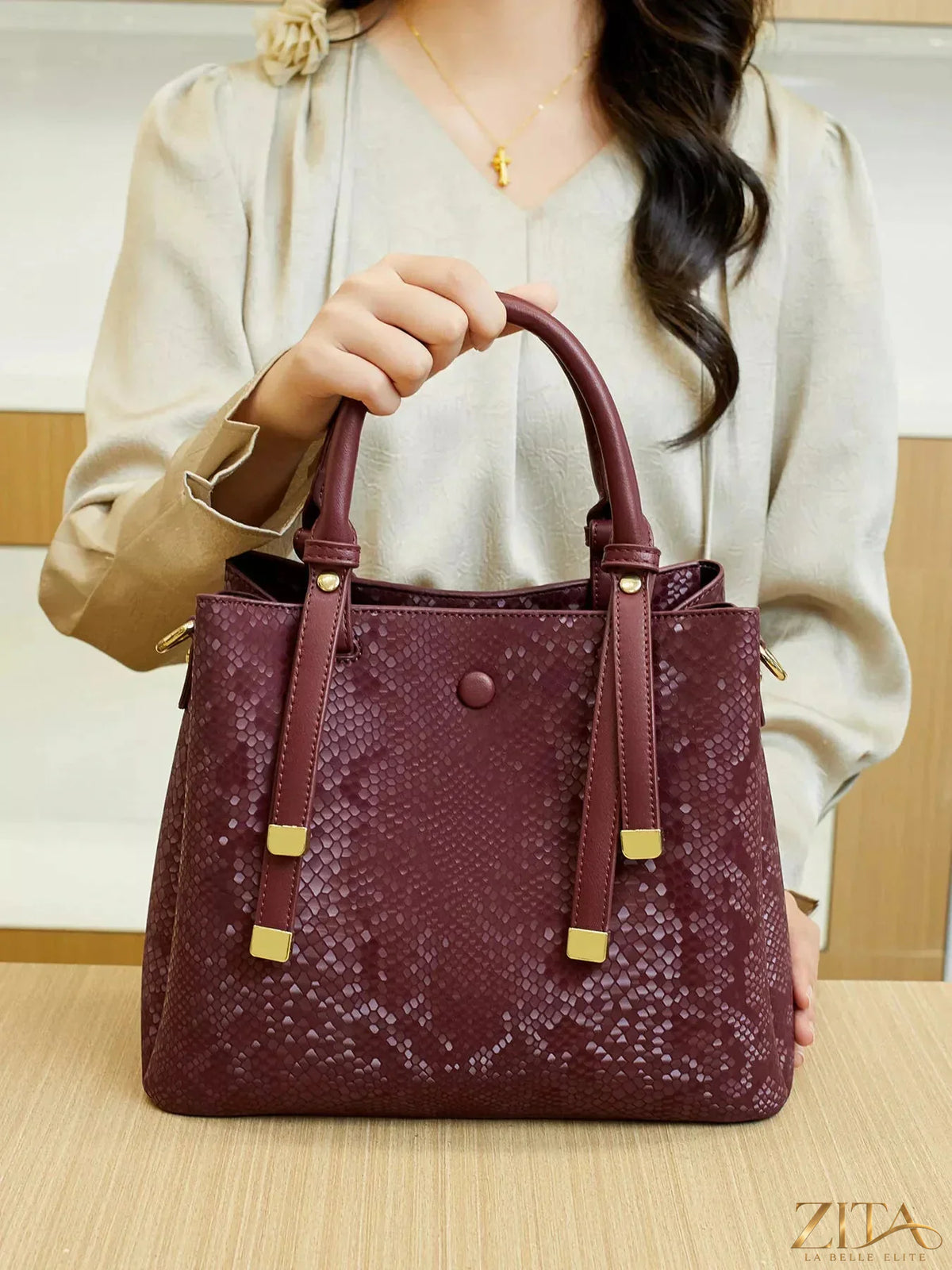 Zita La Belle Elite snakeskin pattern handbag with gold hardware and structured shape, featuring a top handle and sleek design.