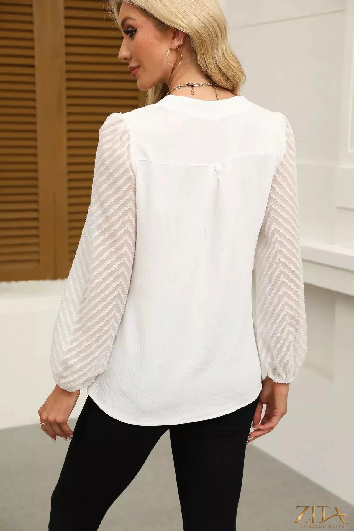 Zita La Belle Elite notched balloon sleeve blouse with ruffled neckline and flowy fabric, shown on a hanger.