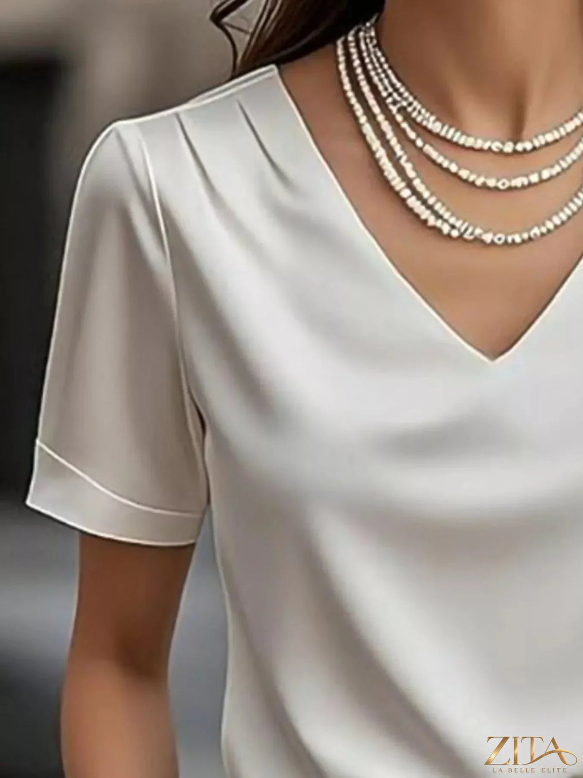 Zita La Belle Elite V-neck short sleeve satin blouse in elegant fabric, displayed on a hanger against a neutral background.