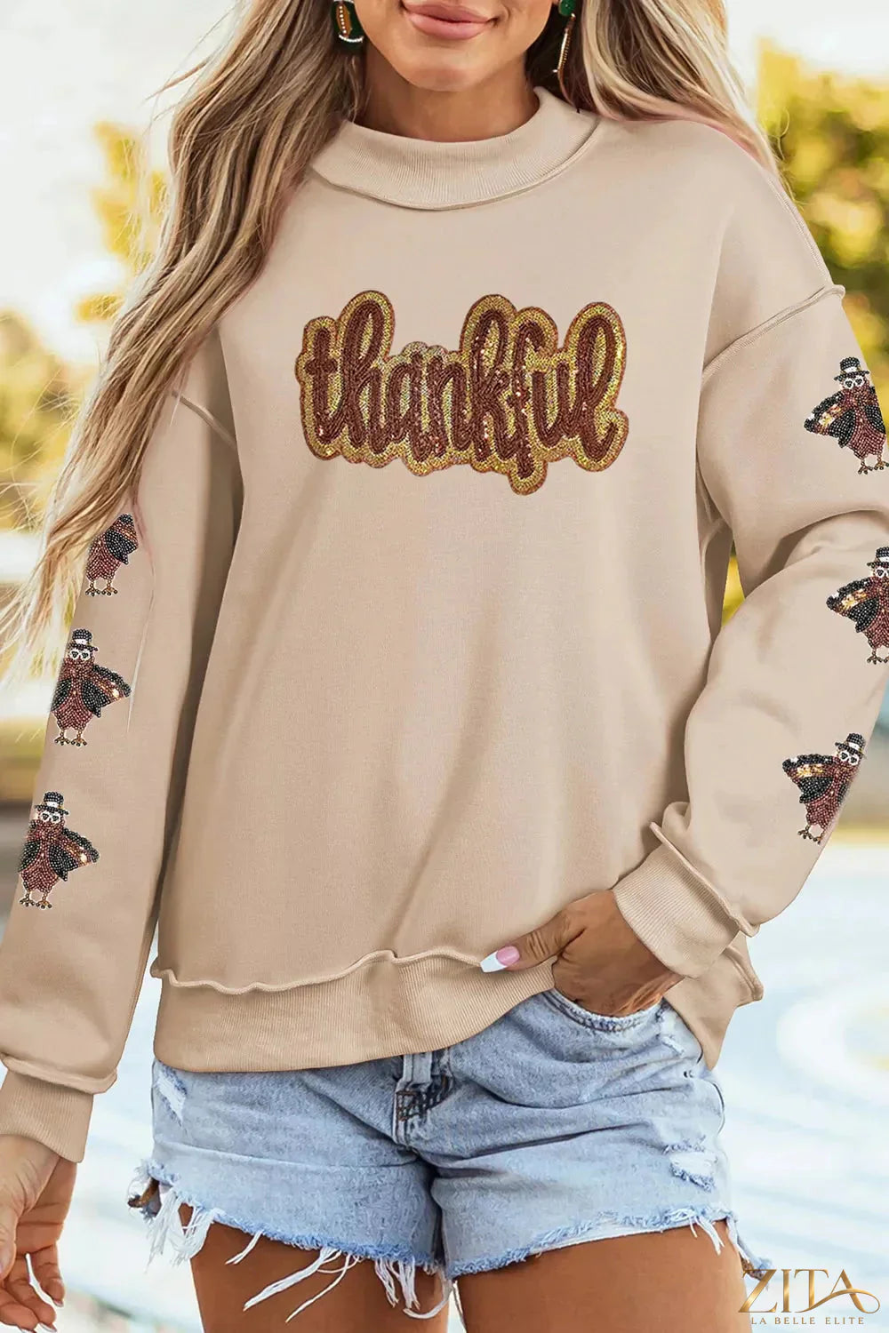 Thankful sequin mock neck sweatshirt by Zita La Belle Elite, featuring shimmering sequins and a cozy fit on a casual model.