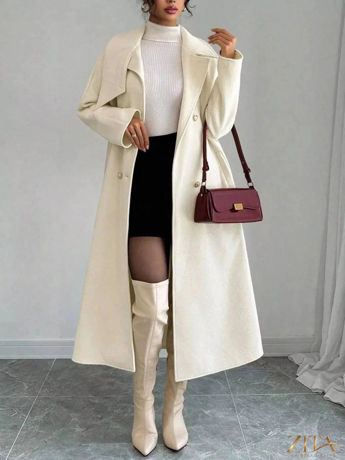 Zita La Belle Elite double-breasted longline coat in neutral fabric, shown hanging on a rack with a tailored fit and classic style.