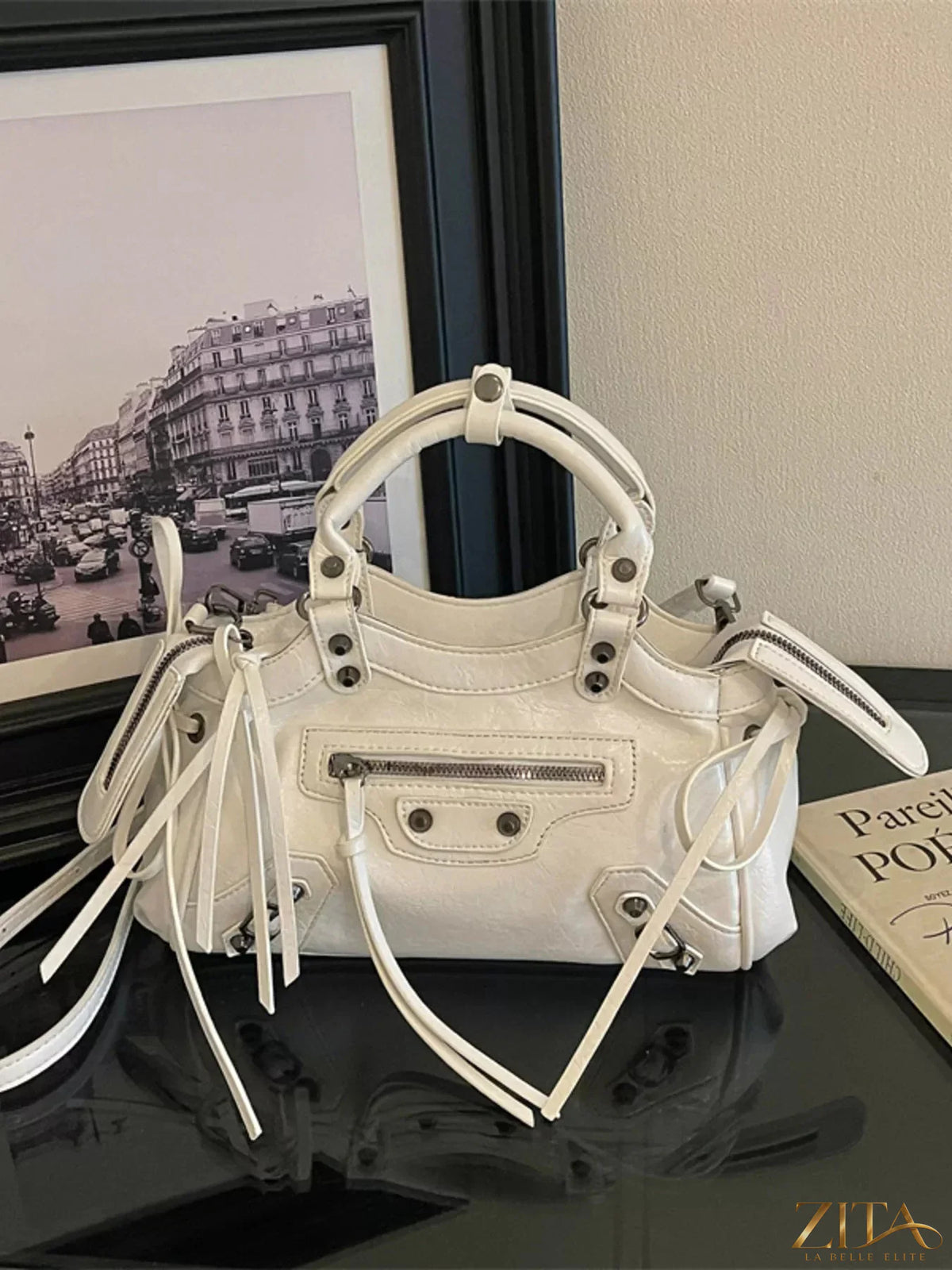 Leather tassel handbag with adjustable strap and gold hardware, featuring a stylish design and spacious interior.