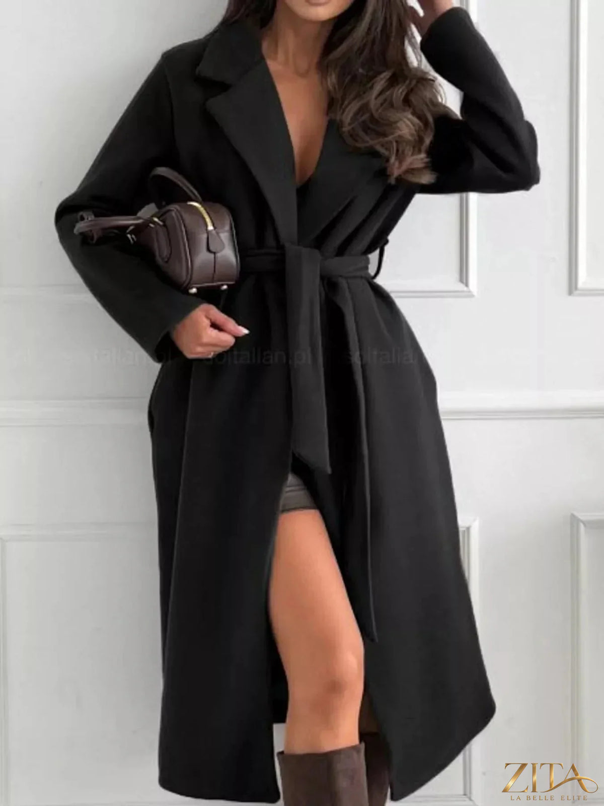 Zita La Belle Elite belted coat with a lapel collar and long sleeves, shown hanging on a wooden background.