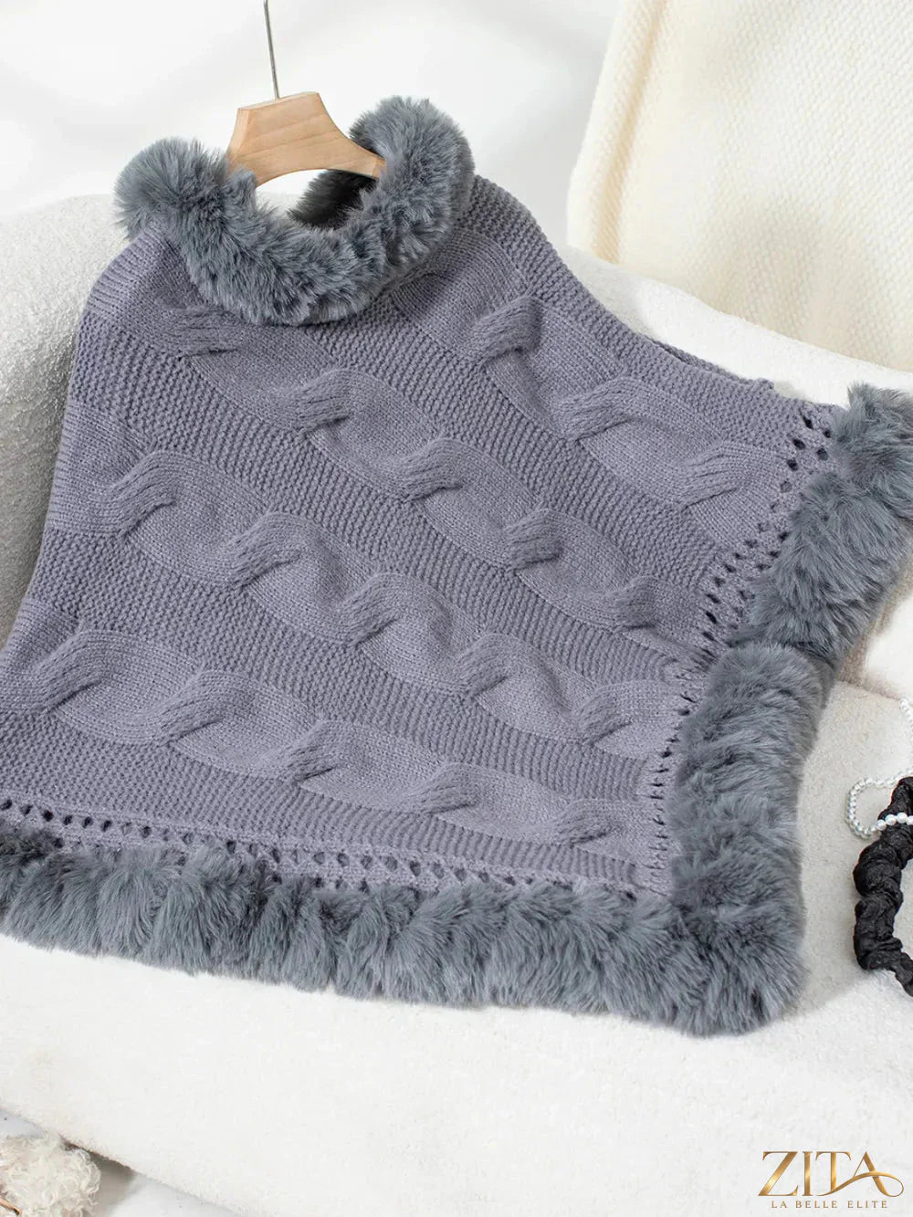 Fuzzy hem cable-knit poncho in neutral tones, featuring a cozy, textured design with ribbed hem and relaxed fit.