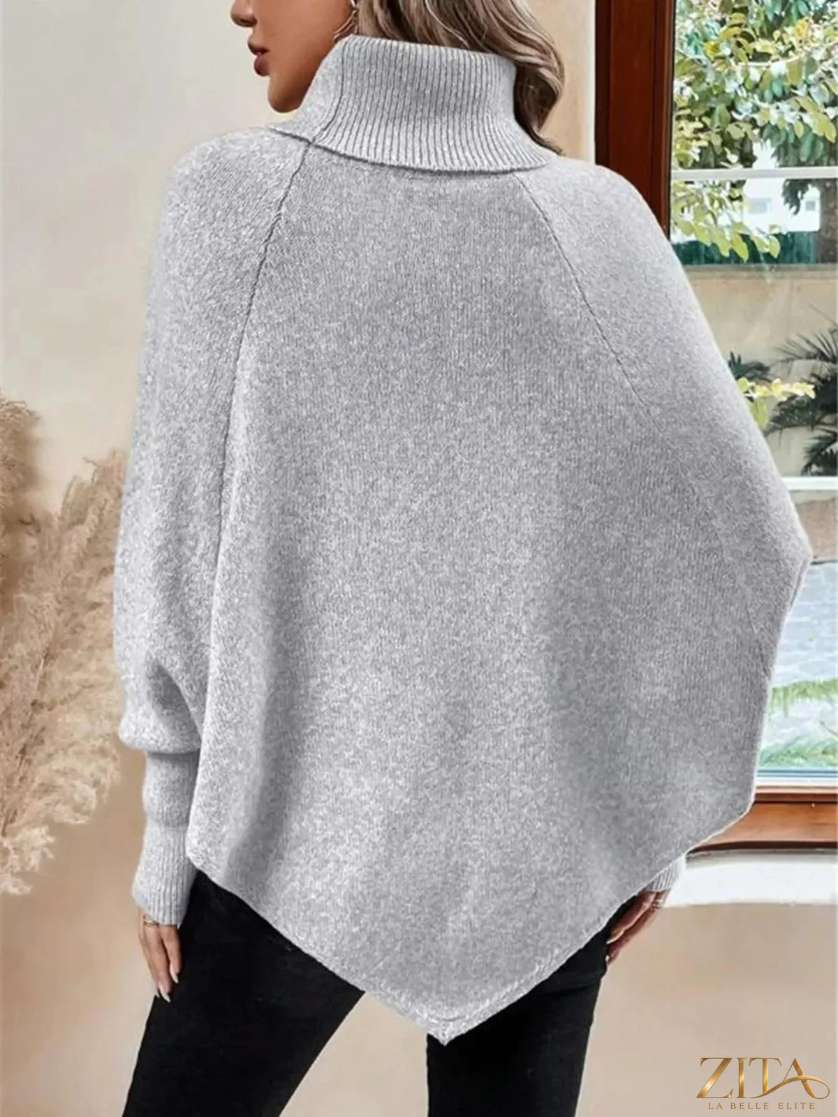 Cable knit turtleneck cape sweater by Trendsi featuring a cozy, oversized design and button details in a neutral color.