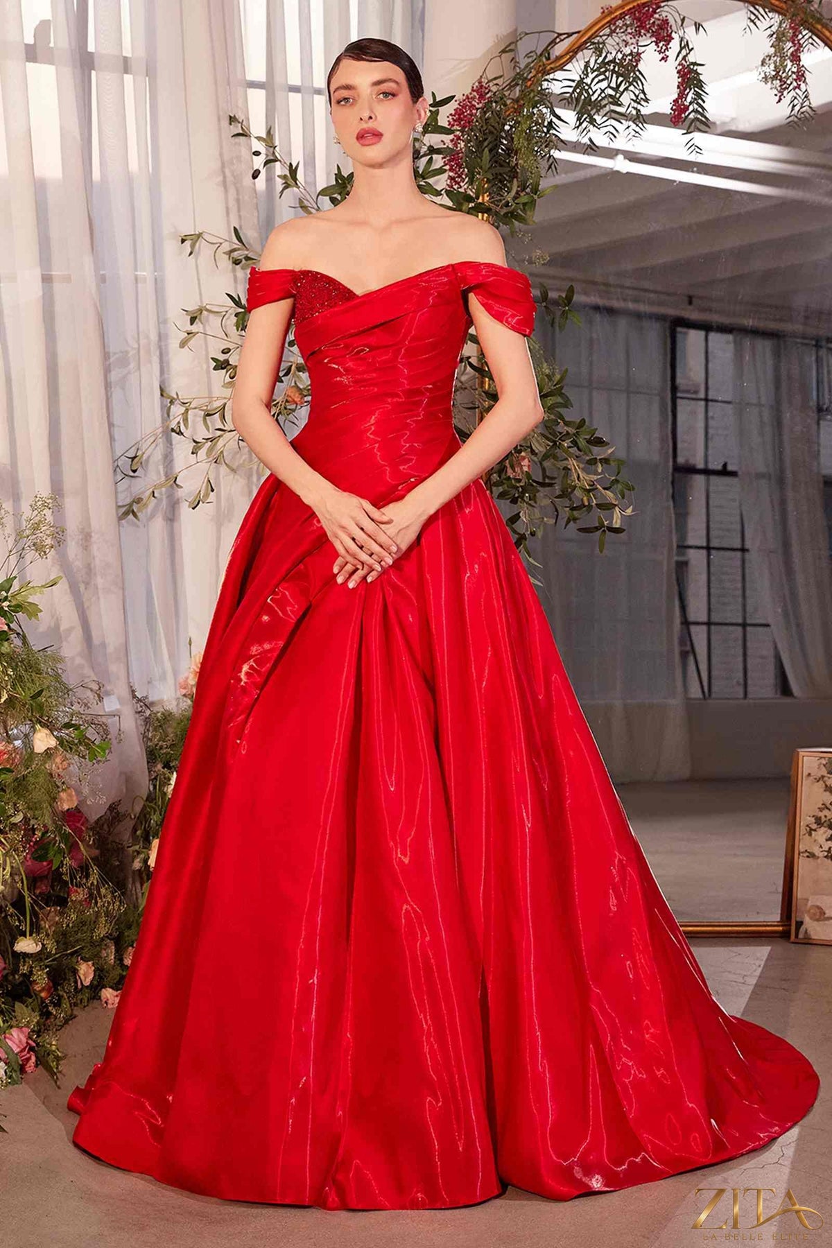 Red off-the-shoulder organza ball gown by Zita La Belle Elite, featuring elegant draping and a flowing skirt.
