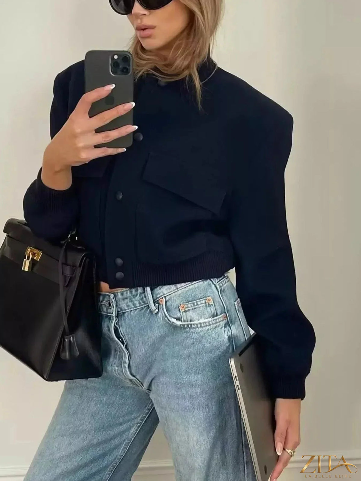 Zita La Belle Elite snap-down cropped bomber jacket in black, featuring a front zipper and ribbed cuffs, displayed on a hanger.