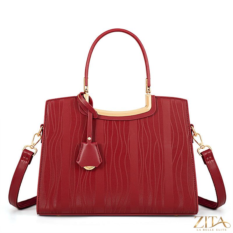 Zita La Belle Elite leather top handle handbag with structured design and gold-tone hardware on a neutral background.