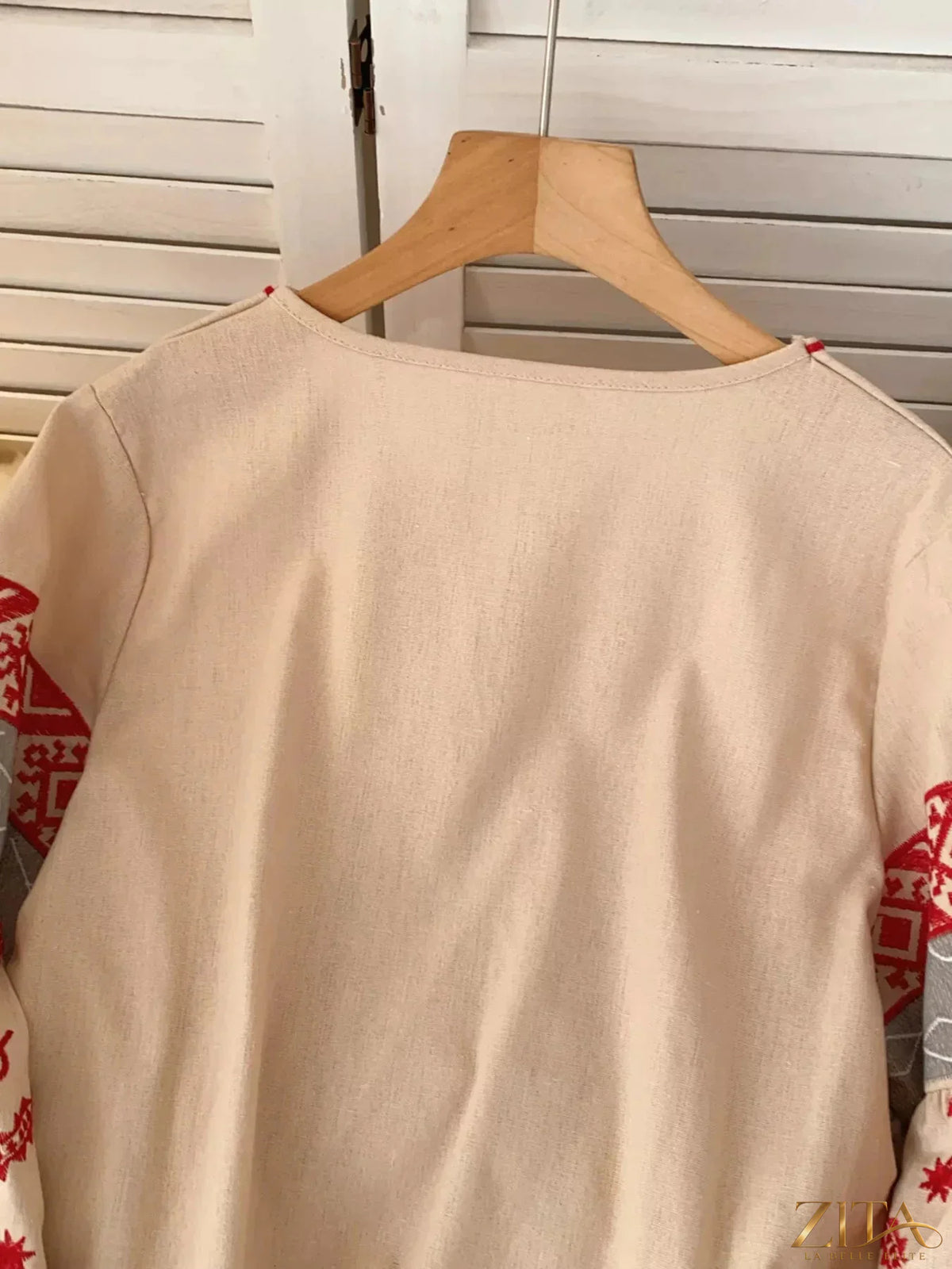 Zita La Belle Elite embroidered tie neck blouse with floral pattern and long sleeves, displayed on a hanger.