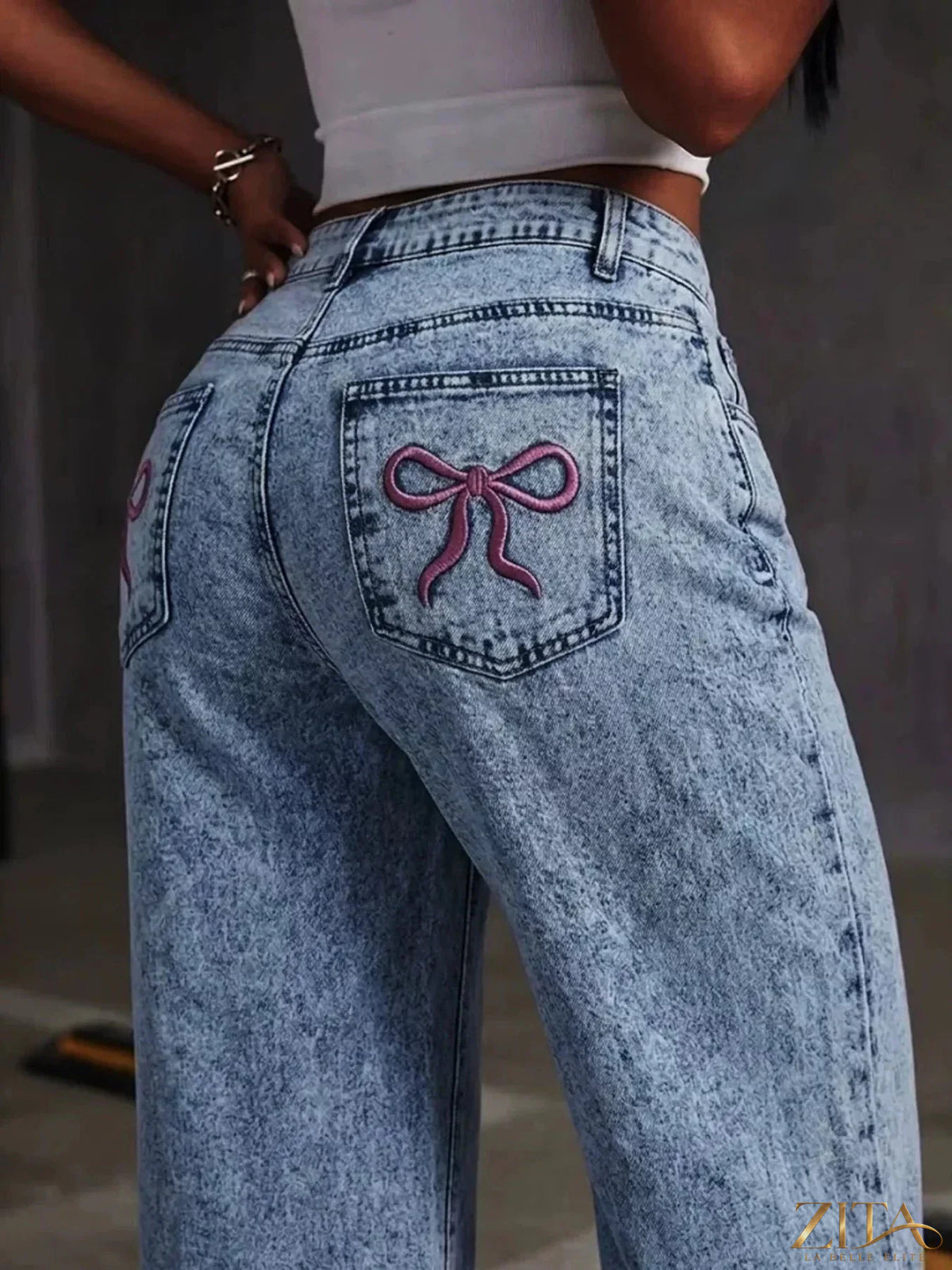 Washed wide leg jeans by Zita La Belle Elite with embroidered bow detail on the back, showcasing relaxed fit and stylish design.