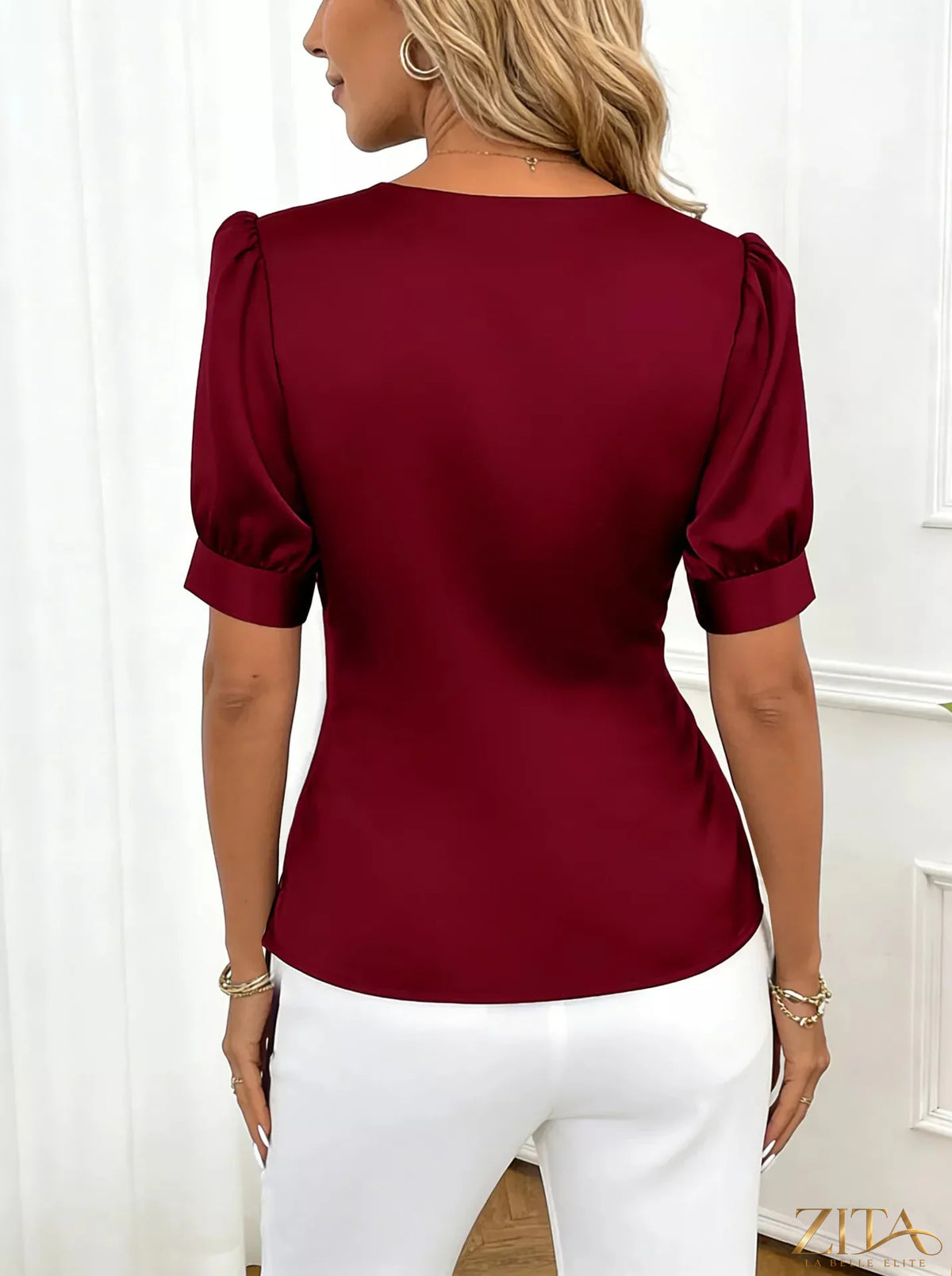 Zita La Belle Elite satin surplice short sleeve blouse with elegant draped neckline and smooth fabric, displayed on a hanger.