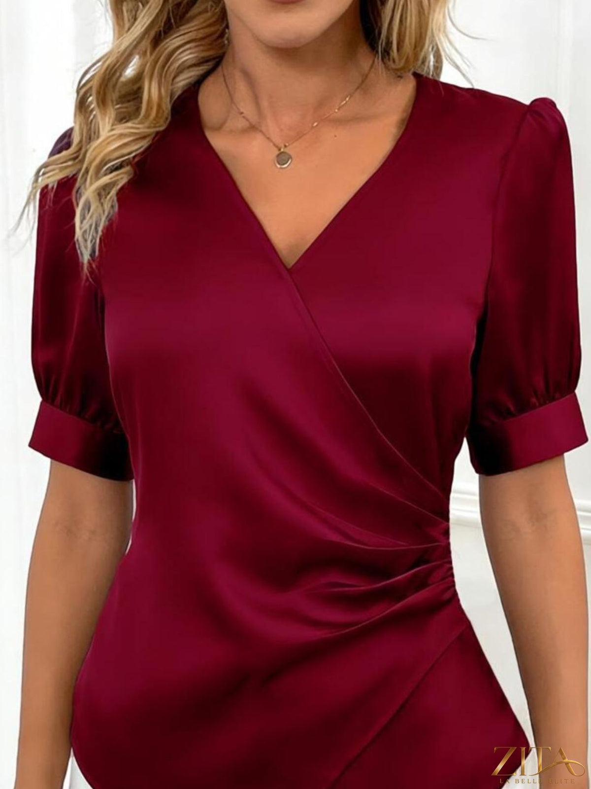Zita La Belle Elite satin V-neck wrap blouse with long sleeves and elegant drape, displayed on a hanger.