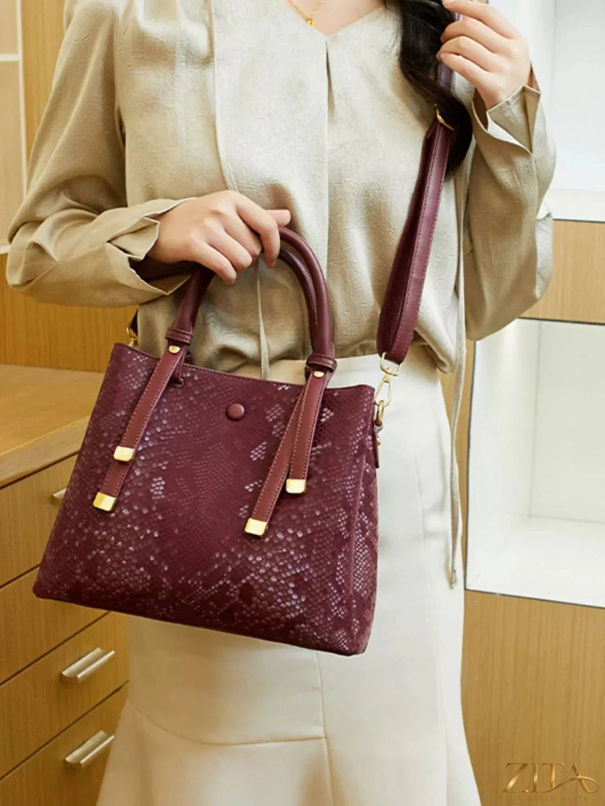 Zita La Belle Elite snakeskin pattern handbag with gold-tone hardware and structured design on a neutral background.
