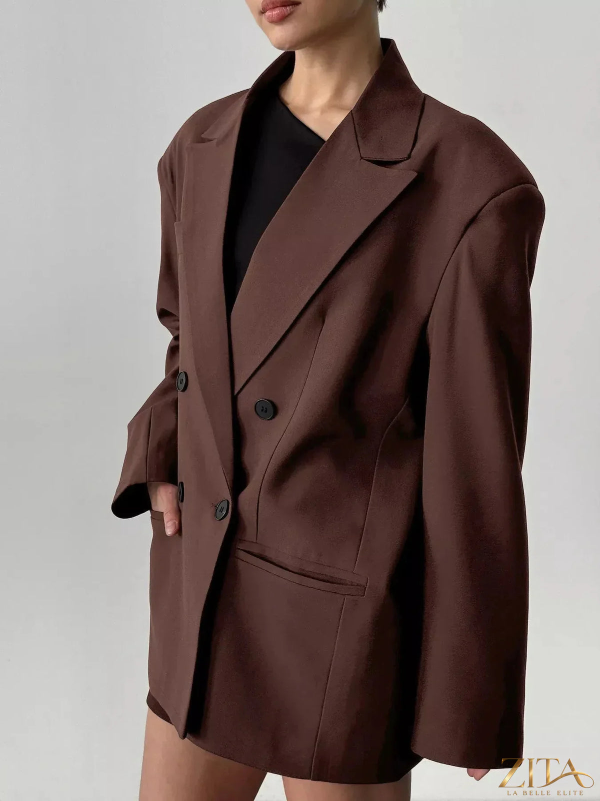 Black double-breasted blazer with lapel collar and structured fit, styled with long sleeves and front buttons.