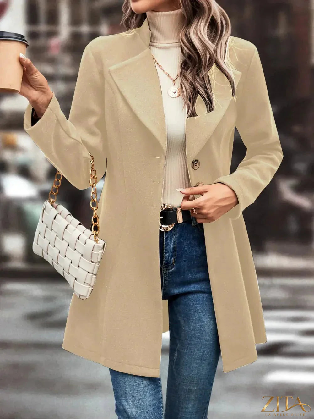Zita La Belle Elite button-up longline coat hanging on a rack, featuring a classic collar and tailored fit in neutral fabric