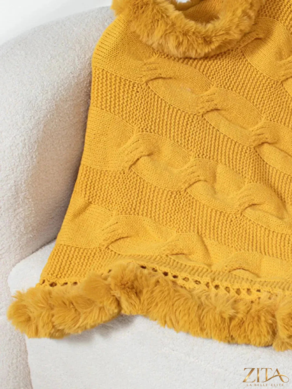 Fuzzy hem cable-knit poncho in cozy beige featuring a relaxed fit and textured pattern, perfect for layering and casual wear.