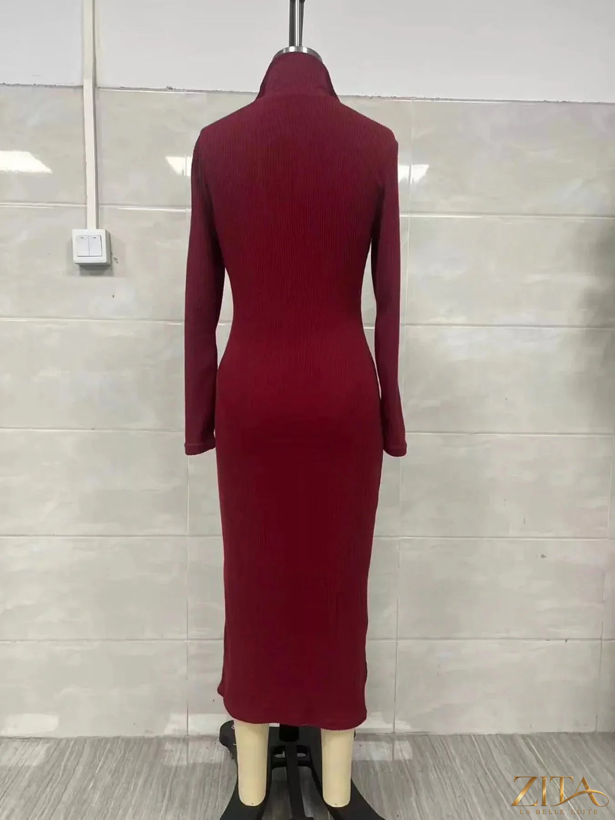 Zita La Belle Elite ribbed knit V-neck sweater dress hanging on a wooden rack, showcasing its textured fabric and classic design.