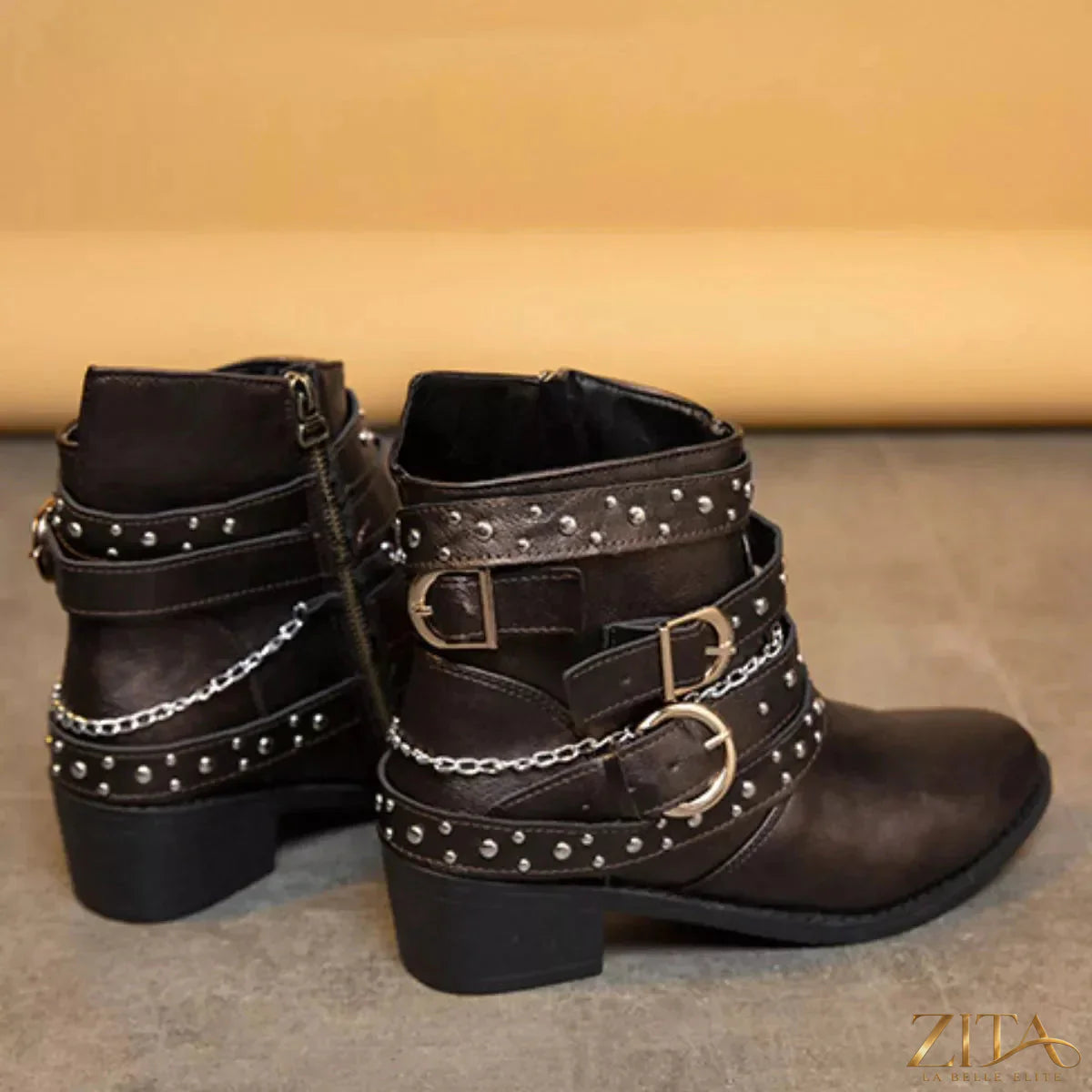 Zita La Belle Elite studded buckle ankle boots with leather straps and metal embellishments on a black leather surface