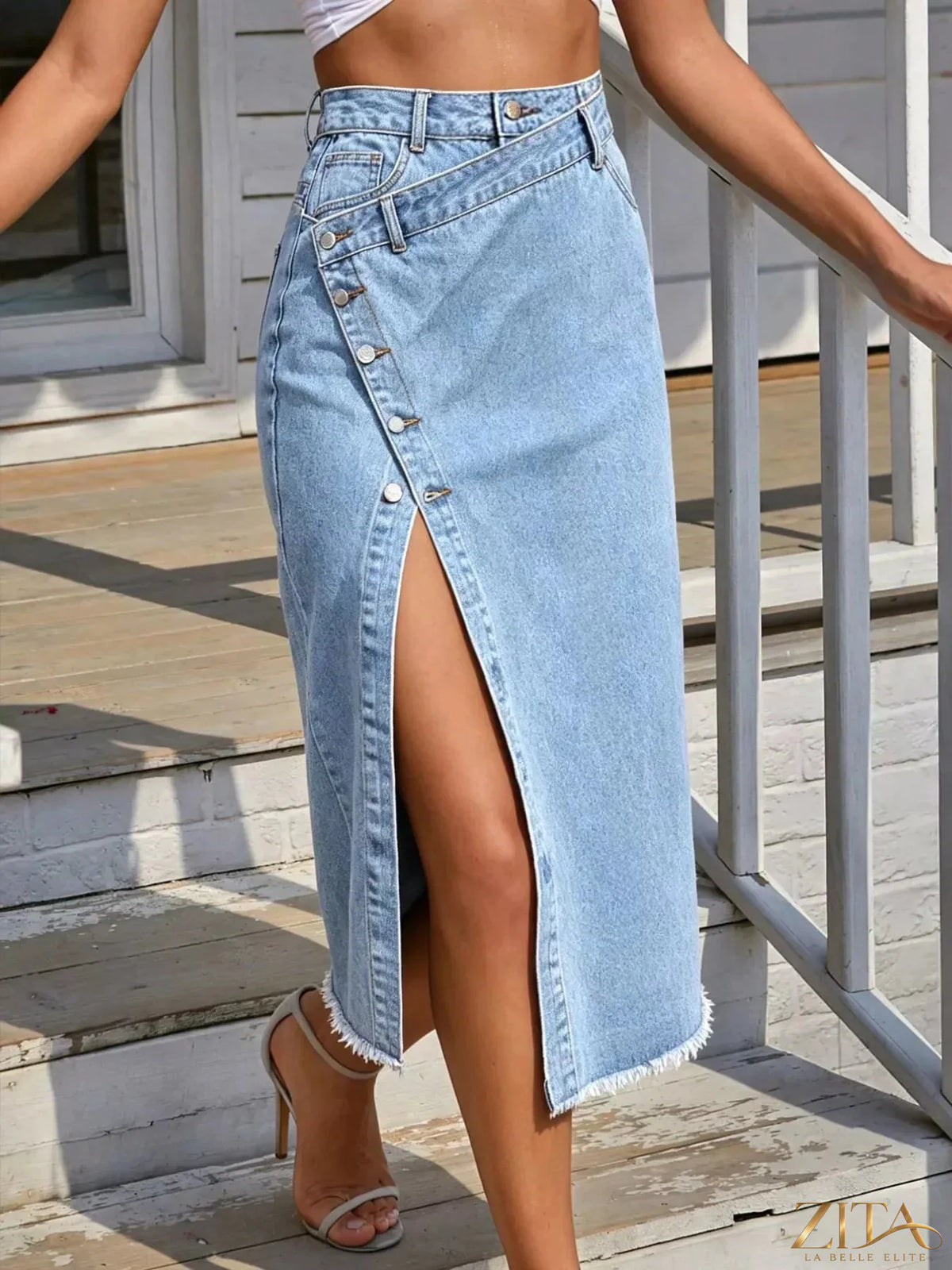 Zita La Belle Elite asymmetric denim midi skirt with button-front and raw hem, shown on a model in a casual setting.