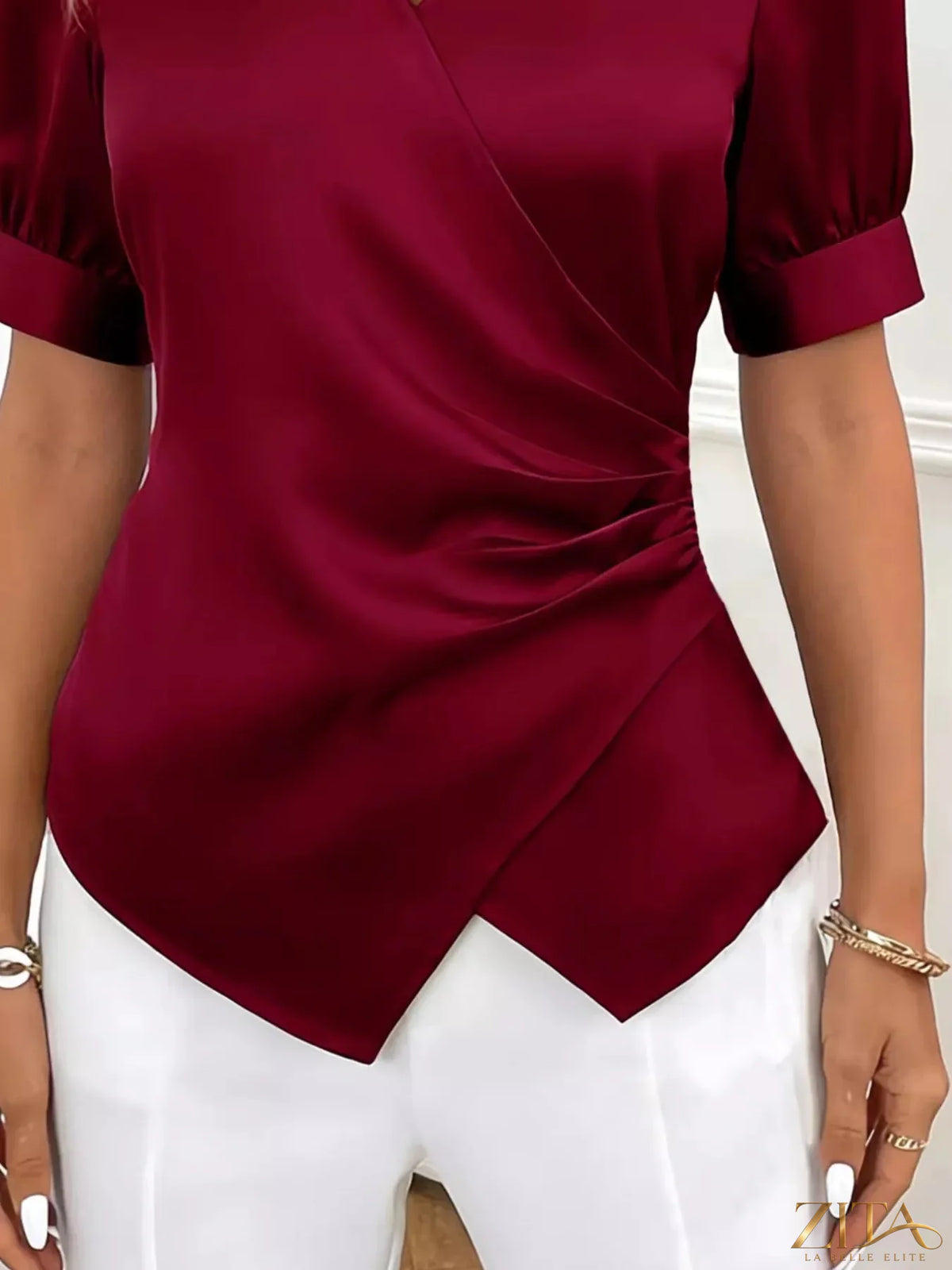 Zita La Belle Elite satin surplice short sleeve blouse with V-neck and elegant draping, displayed on a hanger.