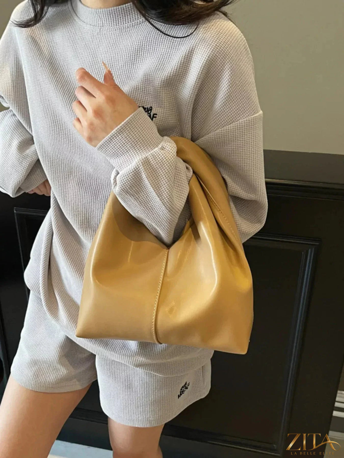 Zita La Belle Elite leather handbag with knot handle, stylish and compact design, black leather with gold-tone hardware.