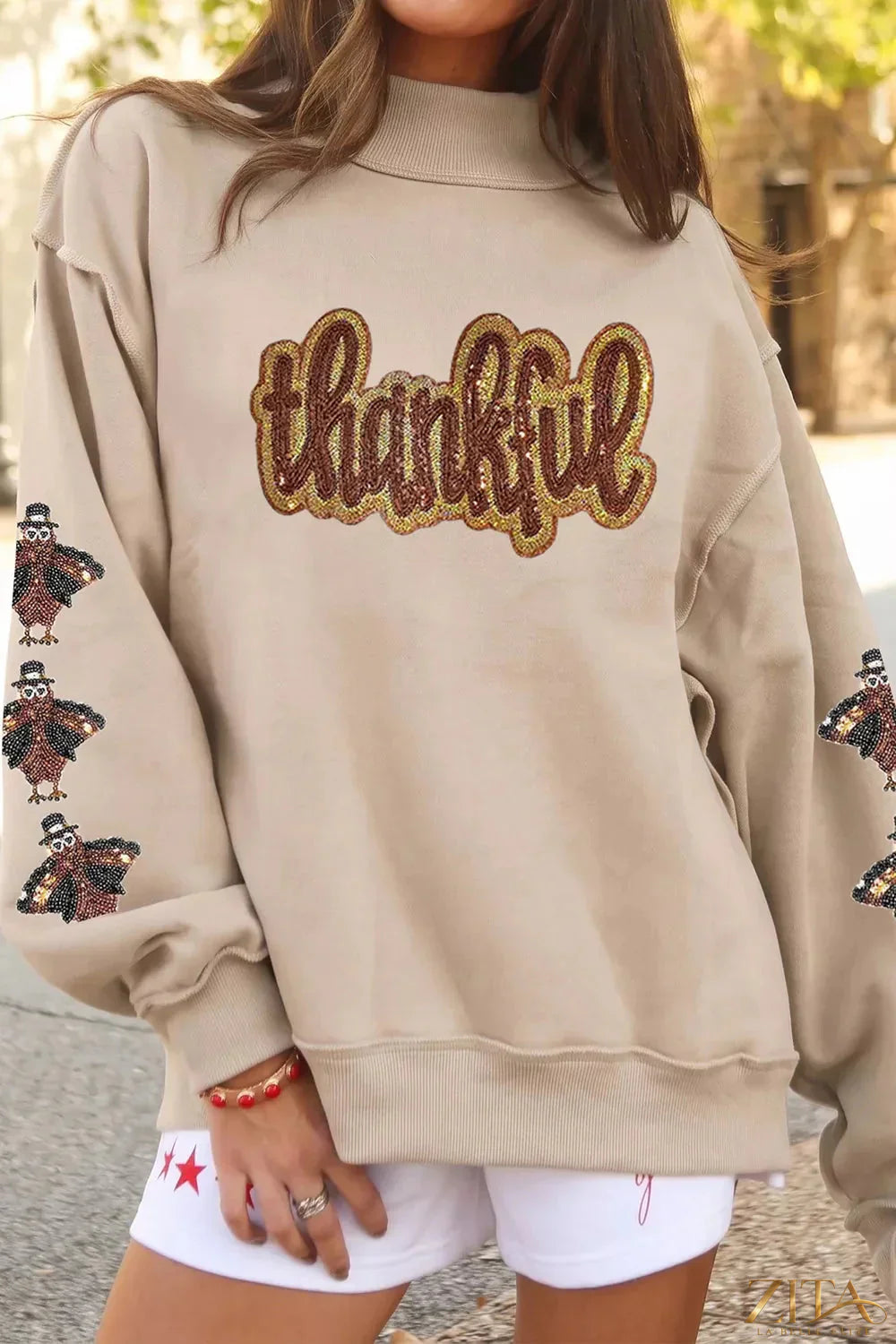 Thankful sequin mock neck sweatshirt by Zita La Belle Elite featuring glittery sequins and a cozy fit, displayed on a hanger.