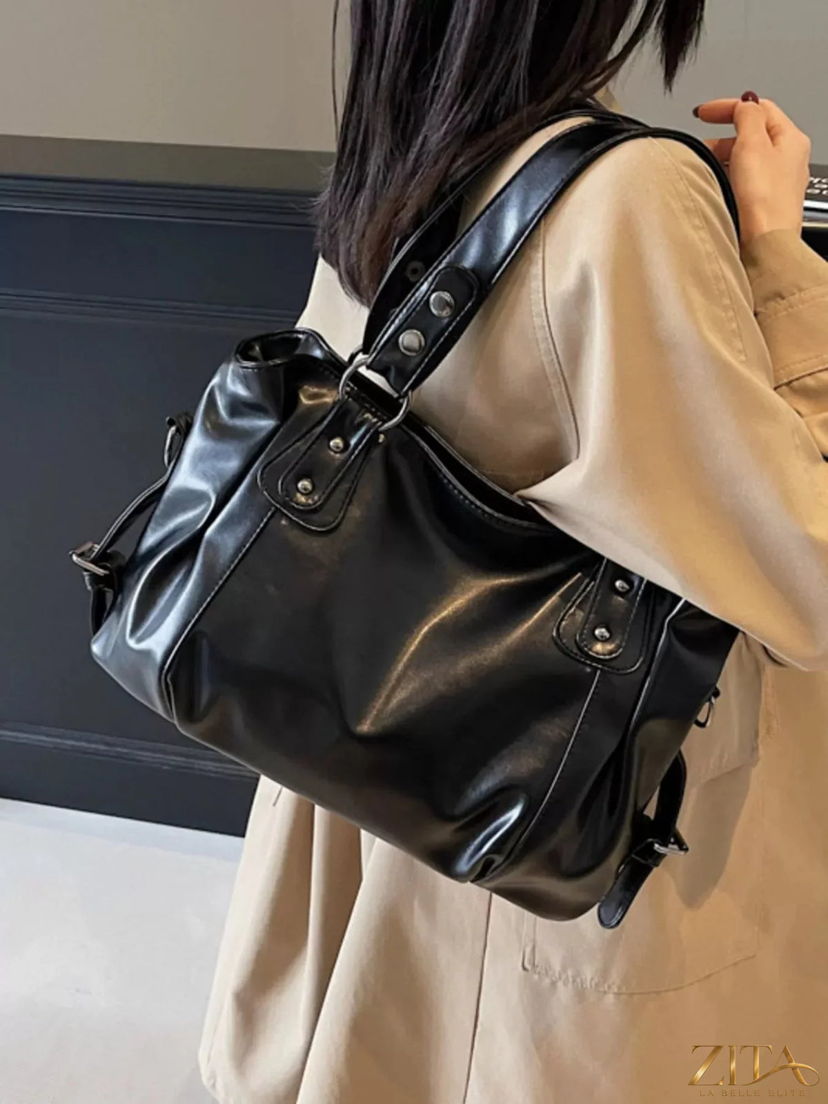 Vintage style leather handbag with adjustable strap and brass hardware, displayed on a neutral background.