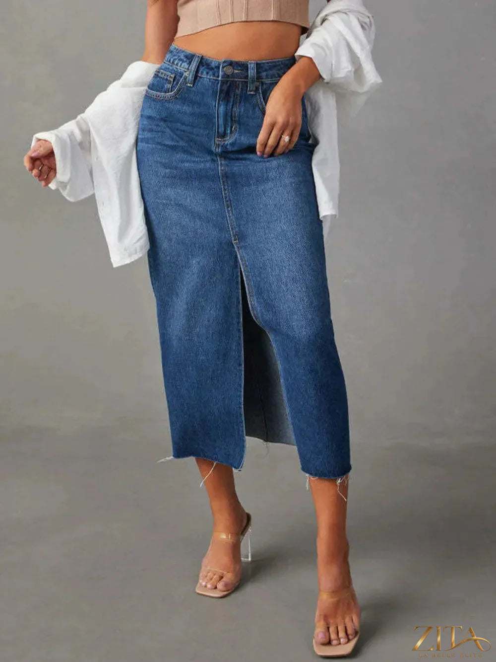 Zita La Belle Elite raw hem front slit denim midi skirt displayed on a hanger, showcasing distressed hem and classic blue denim fabric.