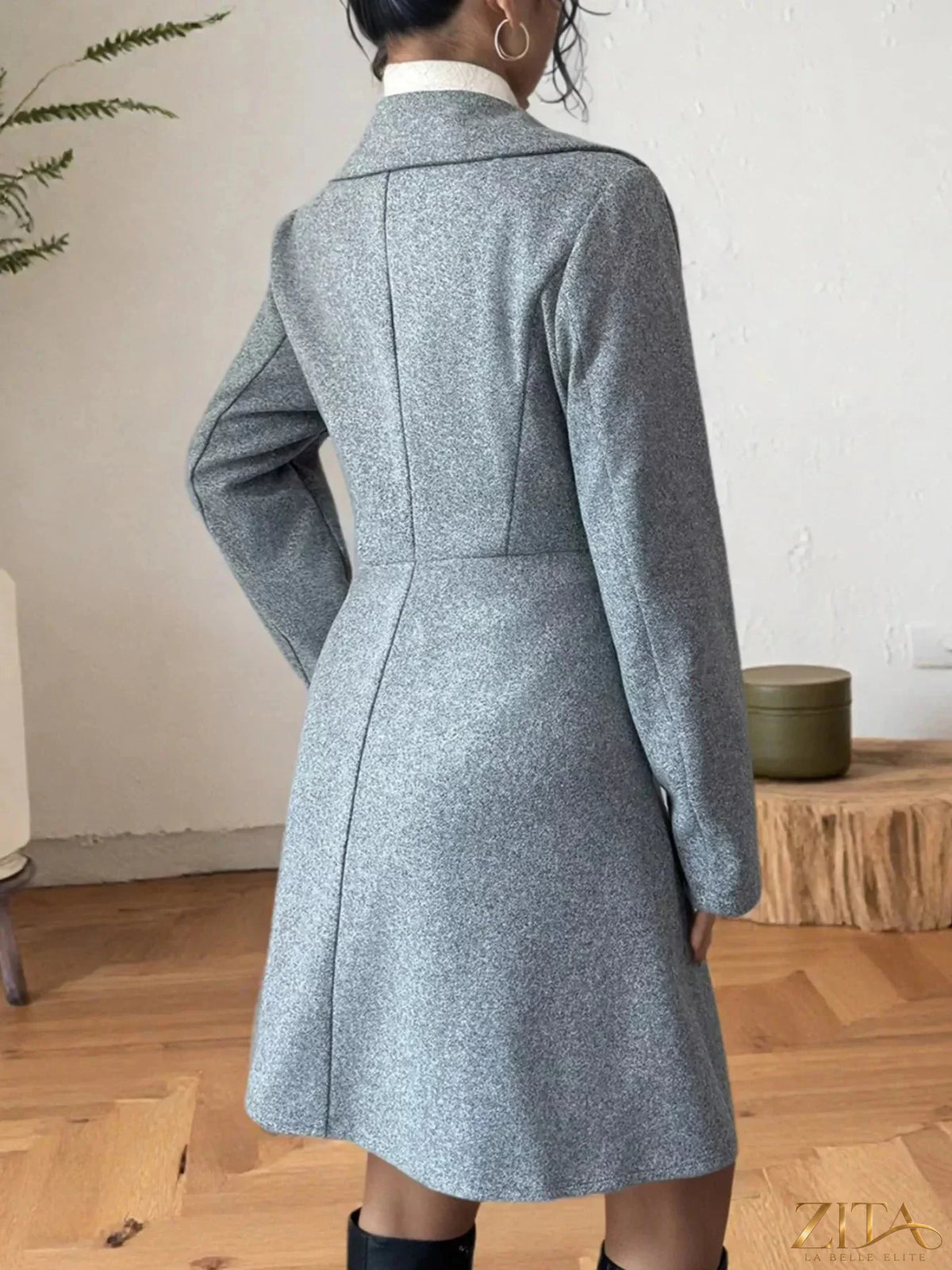 Zita La Belle Elite double-breasted wool blend coat hanging on a wooden rack, showcasing its tailored lapels and stylish design.