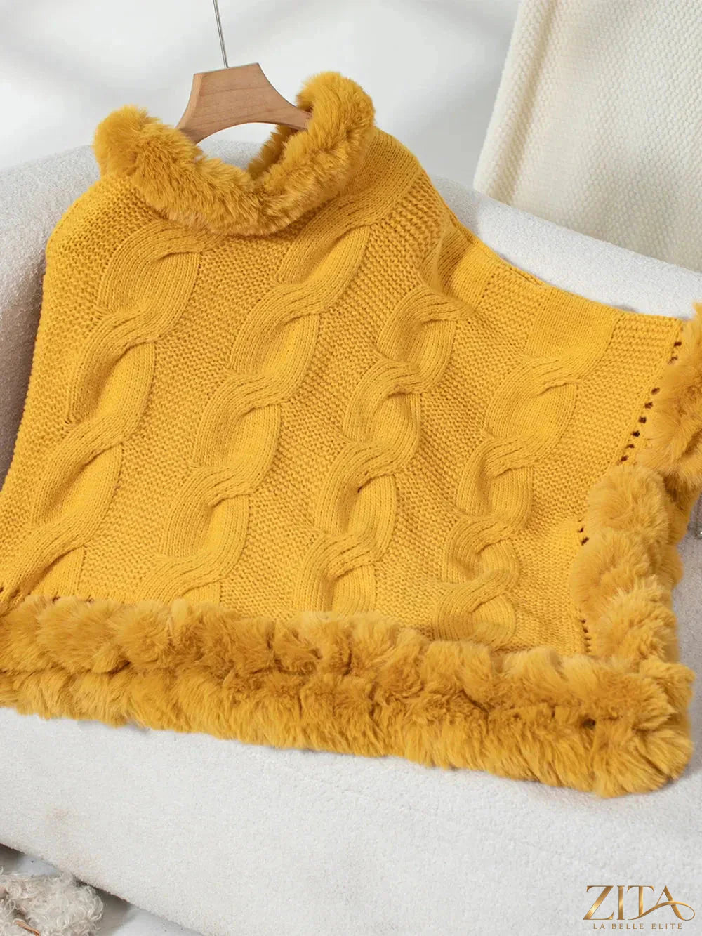 Fuzzy hem cable-knit poncho in neutral color, featuring a cozy, textured design and relaxed fit from Trendsi.