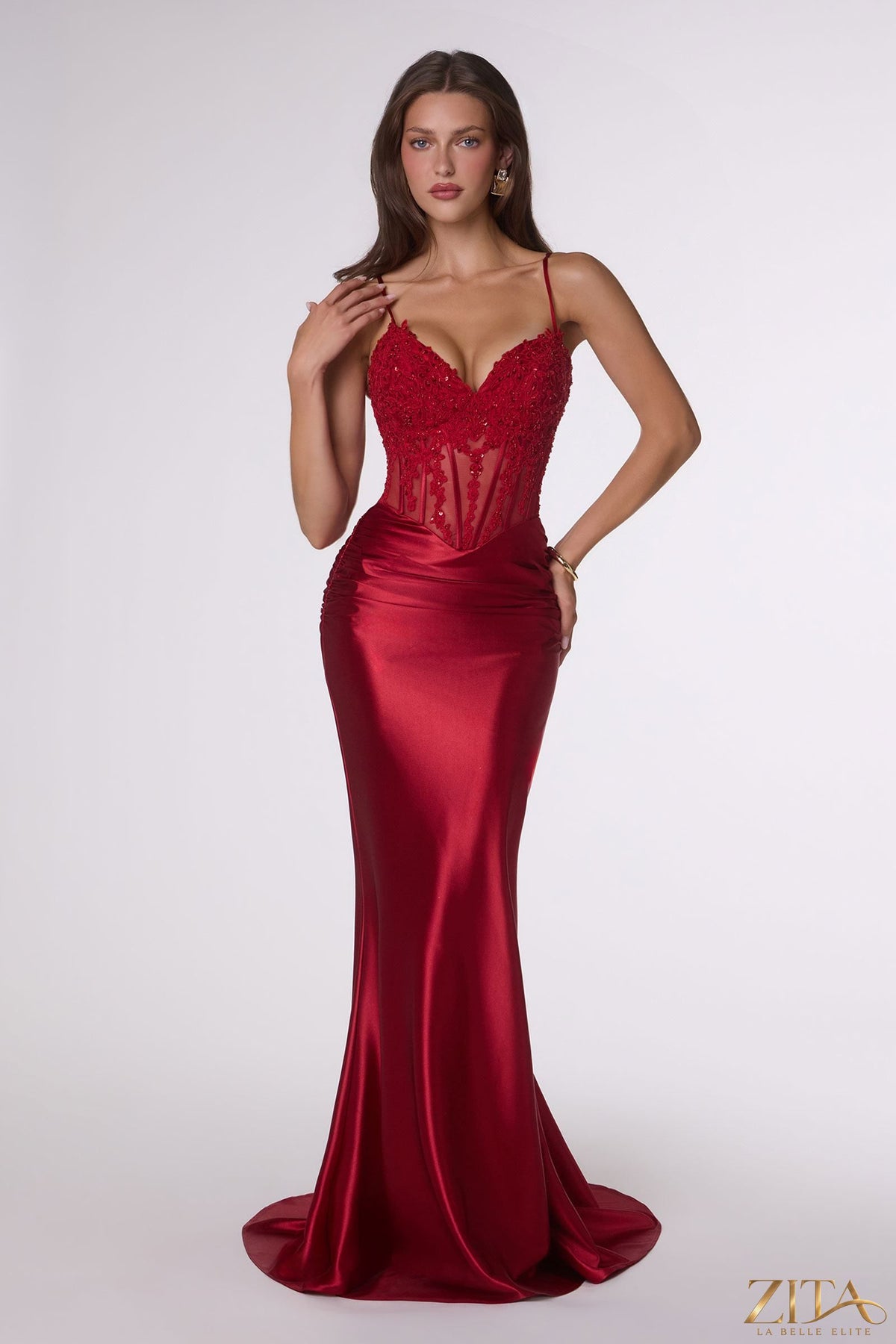 Red fitted stretch satin corset mermaid gown by Zita La Belle Elite, showcasing a sleek, sheer design with a flattering silhouette.