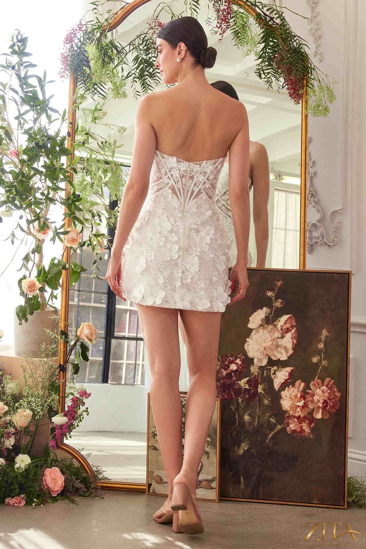 Off-white strapless sweetheart midi bridal dress by Zita La Belle Elite, featuring a fitted bodice and flowing skirt from the back view.
