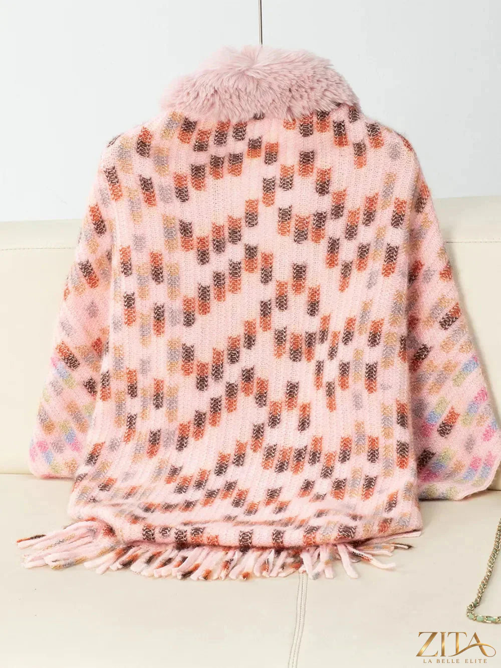 Fuzzy open front fringe poncho in neutral tones with tassel details, stylish and cozy fashion layer.
