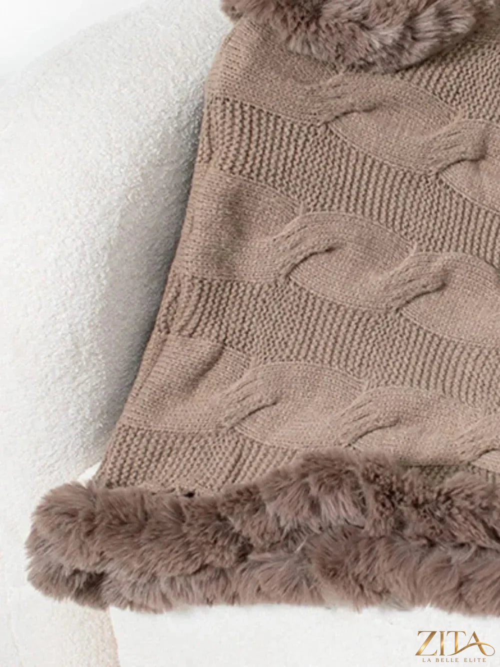Fuzzy hem cable-knit poncho in neutral tones, featuring cozy, textured knit with a relaxed fit and stylish design.