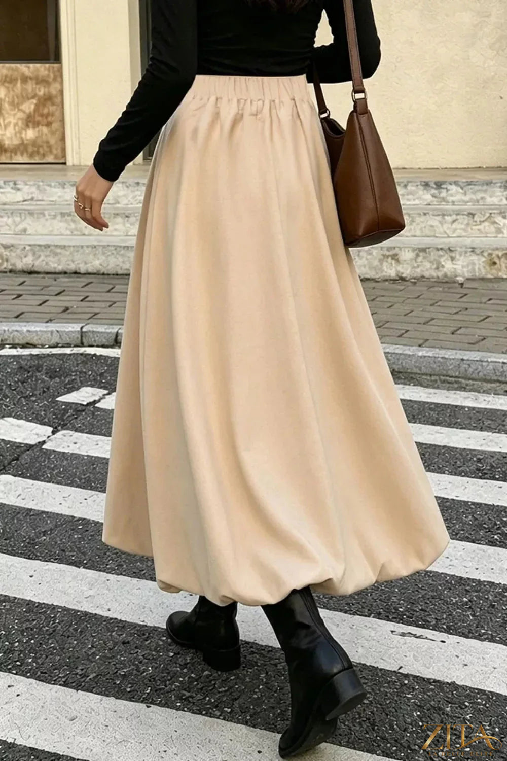 High-waisted A-line midi skirt from Trendsi displayed on a model, showcasing a flowy, elegant design in a neutral color.