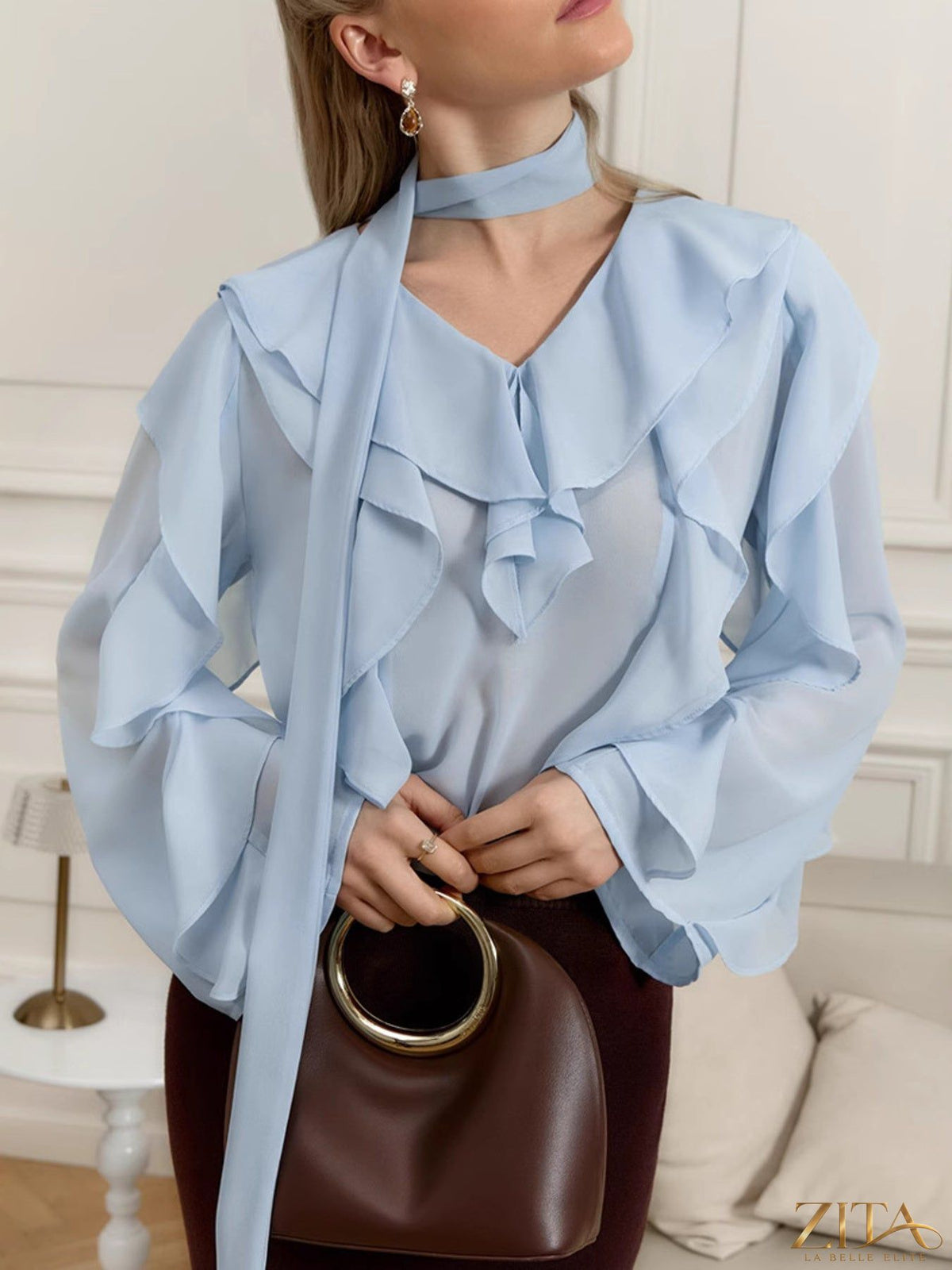 Zita La Belle Elite chiffon blouse with ruffle trim, featuring lightweight fabric and elegant design, displayed on a hanger.