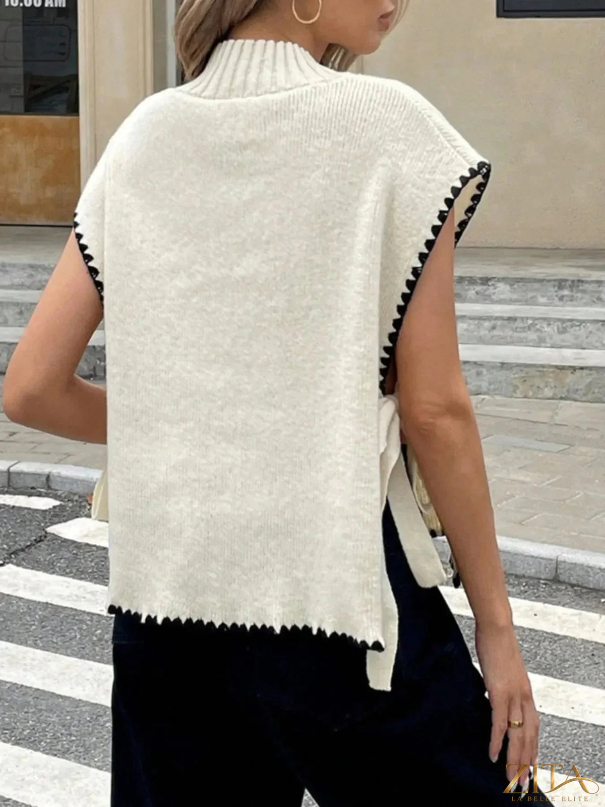 Ribbed turtleneck sweater vest with contrast trim in neutral tones, styled with layered clothing for a trendy look.