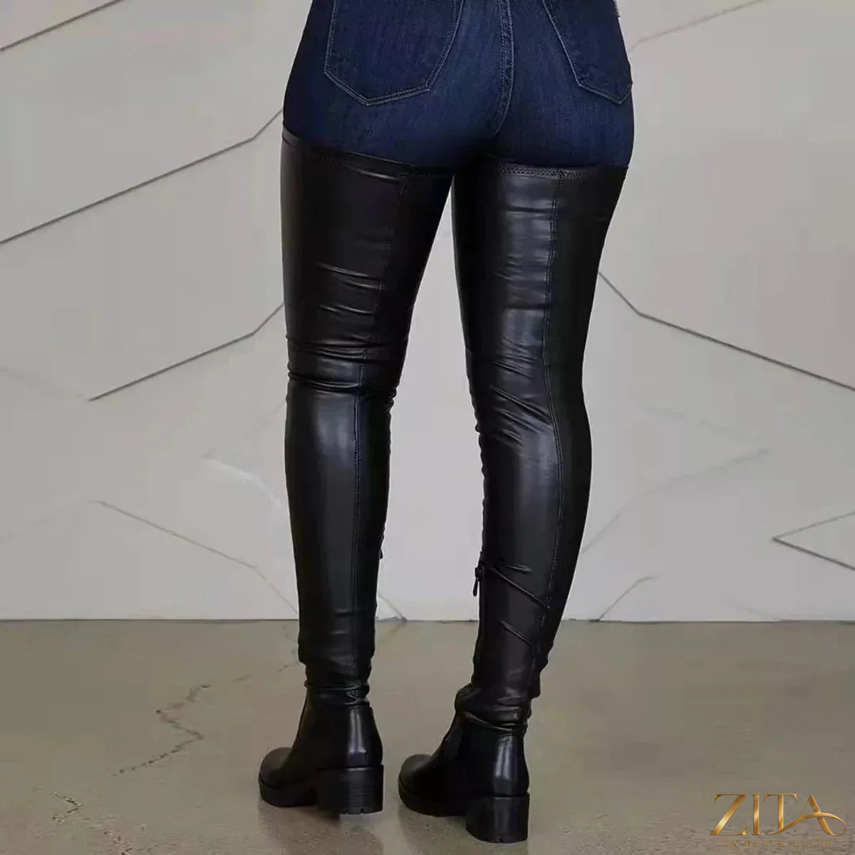 Over-the-knee block heel boots in black leather with pointed toes and chunky heels, stylishly displayed on a model.