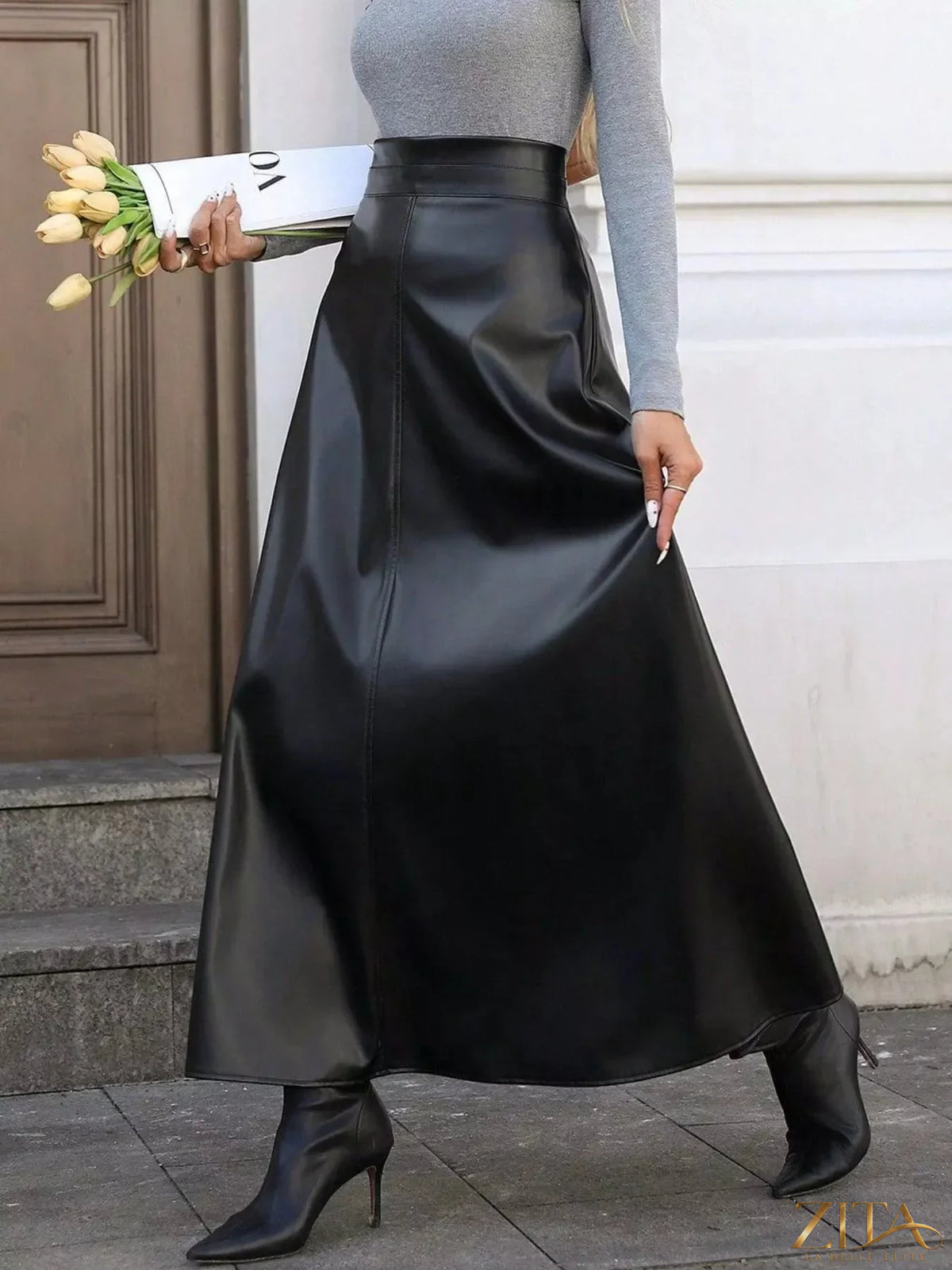 Black leather A-line midi skirt by Trendsi, featuring a smooth texture and classic silhouette, displayed on a neutral background.