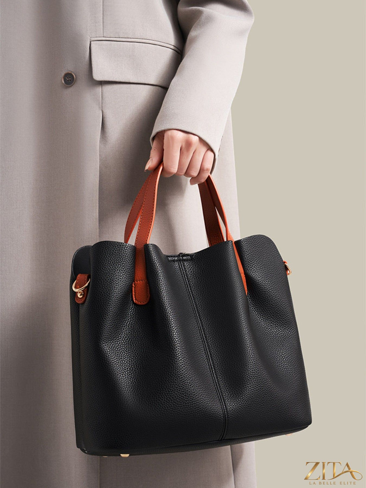 Leather contrast handle handbag with sleek design and top zipper closure, featuring trendy black and tan color blocks.