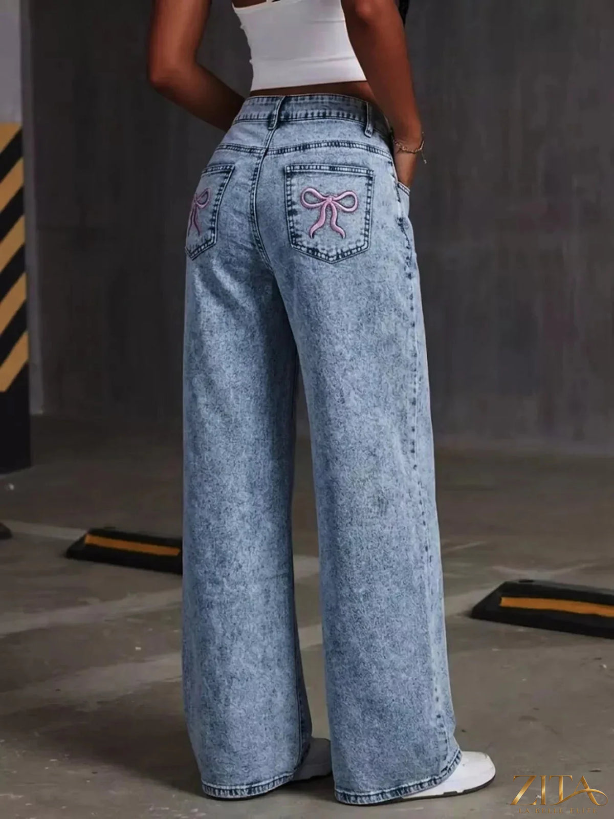 Washed wide leg jeans by Zita La Belle Elite with embroidered bow detail and relaxed fit, shown in a light denim wash.