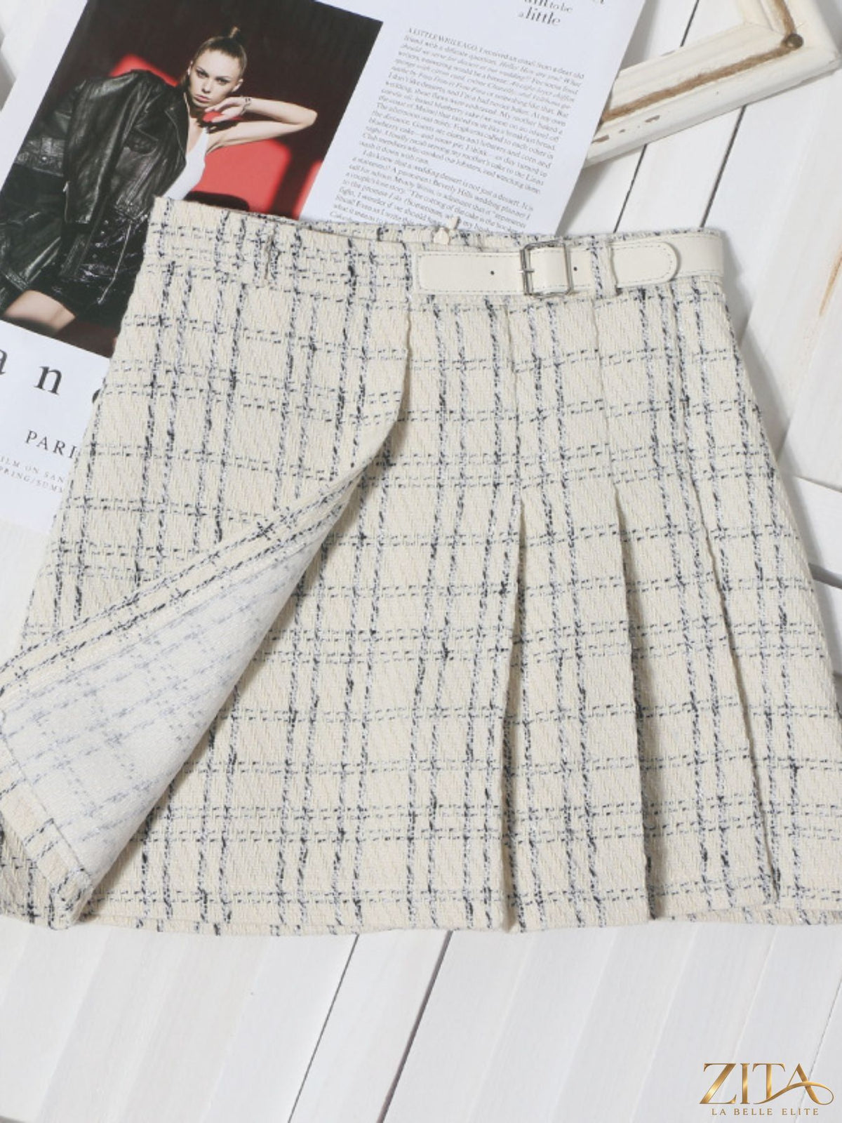 Zita La Belle Elite pleated plaid mini skirt displayed on a hanger, featuring classic tartan pattern and stylish high-waist design.