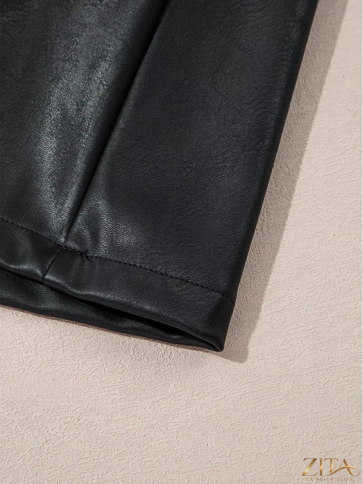 Zita La Belle Elite vegan leather sleeveless mini dress hanging on a white background, showcasing its sleek design and smooth texture.